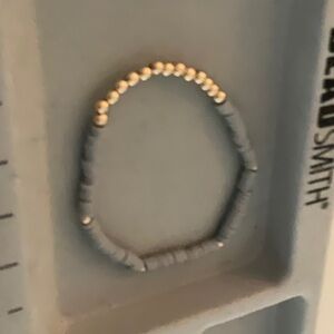 A gray clay beaded bracelet with gold beads